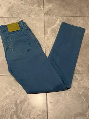 Jacob Cohën jeans - Stiliga jeans från märket Jacob Cohën, en unik ljusblå färg som ger de speciella. Har också en läderpatch och ett broderat J på fickan. Röda detaljer på insidan ger de en snygg look. Storleken är i W32.