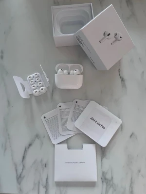 Apple AirPods Pro trådlösa hörlurar - Säljer ett par vita Apple AirPods Pro med  extra silikonpluggar. Hörlurarna har en stilren och kompakt design i blank plast och levereras med originalförpackning och manualer. Perfekta för dig som vill ha grymt ljud och smidig anslutning till din iPhone.
