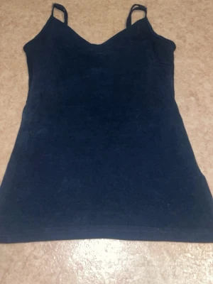 Mörkblå linnetopp med smala band - En enkel och stilren mörkblå linnetopp med smala axelband. Toppen har en rak passform och ärmlös design, perfekt för varma dagar eller som lager under en skjorta. Materialet känns mjukt och bekvämt mot huden.