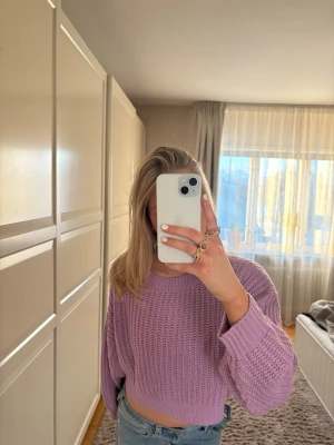 Ljuslila cropped stickad tröja - Säljer en ljuslila cropped stickad tröja! Tröjan har långa, lite pösiga ärmar och en avslappnad passform. Perfekt att styla med jeans för en trendig look.