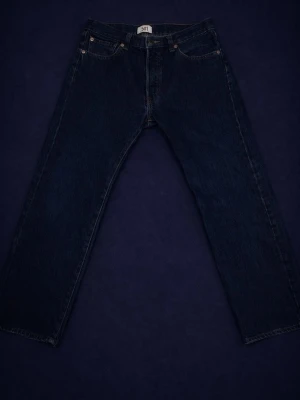 Levi's 501 mörkblå raka jeans - Klassiska Levi's 501 jeans i mörkblå denim med rak passform och fem fickor. Jeansen har knappgylf och tydliga sömmar. Perfekta för dig som gillar tidlös stil och vill ha ett par riktigt schyssta jeans i kraftigt bomullstyg.