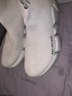 Vita Balenciaga sock sneakers - Unika vita sock sneakers från Balenciaga med stickad ovandel och chunky, futuristisk sula. Modellen har en strumpliknande passform och Balenciaga-logga på sidan. Perfekta för dig som vill sticka ut med en modern och trendig look.