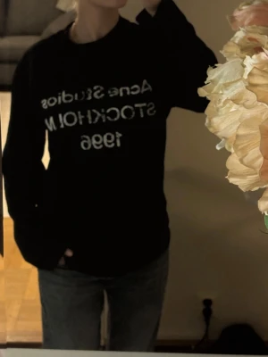 Svart Acne Studios t-shirt med tryck - Svart t-shirt från Acne Studios med vitt tryck på bröstet där det står 'Acne Studios STOCKHOLM 1996'. Klassisk passform och rund halsringning. Perfekt för en clean och stilren look.