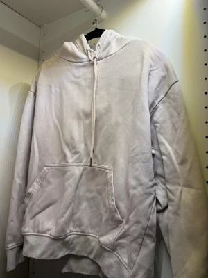 Ljusgrå oversized hoodie - En stilren ljusgrå hoodie med huva och dragsko. Hoodien har en stor känguruficka framtill och är tillverkad i ett mjukt, fleeceliknande material. Perfekt för en avslappnad och trendig look.