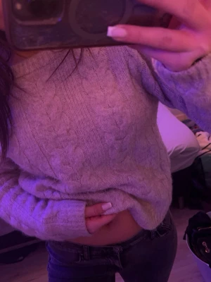 Beige stickad tröja  - Mysig beige kabelstickad tröja med rund halsringning och långa ärmar. Tröjan har ett klassiskt flätmönster och ribbstickade muddar vid ärmslut och nederkant. Perfekt för lager-på-lager och chill dagar.