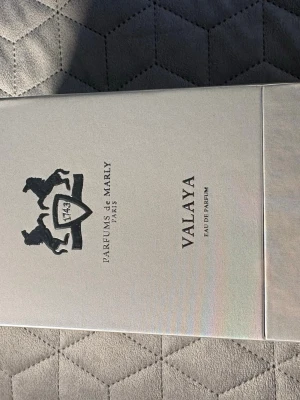 Parfums de Marly Valaya EdP - Lyxig parfym från Parfums de Marly, Valaya Eau de Parfum. Förpackningen är elegant och ljus med en skimrande finish och svart logotyp med två hästar. Perfekt för dig som gillar exklusiva dofter och snygg design.