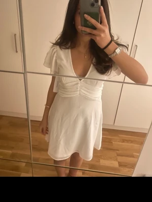 Söt studentklänning - Söt vit kortklänning med v-ringning och volangärmar.Perfekt till studenten! Aldrig använd!