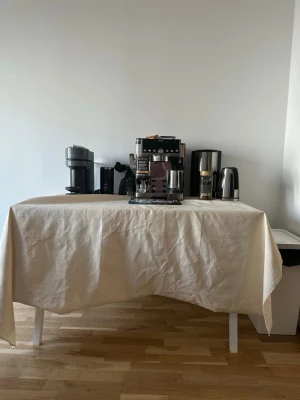 Vitt bord med avtagbar duk - Säljer ett stilrent vitt bord med raka ben i metall och en slät bordsskiva. Bordet har en ljusbeige, avtagbar duk i tyg som täcker hela ytan. Perfekt som extra avlastningsyta eller till servering. Bordet har enkel och modern design som passar in i de flesta rum.