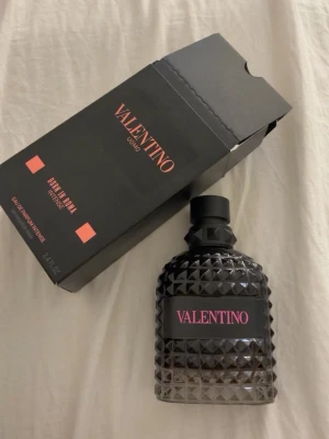 Valentino Uomo Born In Roma Intense - Valentino Uomo Born In Roma Intense är en lyxig parfym i en svart, nitar-inspirerad glasflaska med rosa detaljer. Flaskan har en unik, edgy design och kommer i en matchande svart kartong med rosa text. Perfekt för dig som gillar exklusiva och moderna dofter. 100 ML! (Det är en kill parfym) använd en gång då jag var osäker ifall det var en tjej eller kill parfym annars är den helt ny. Pris går att diskuteras 🤗🤗