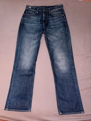 G-Star Jeans W28/L30 - Mörkblå Jeans från G-star i storlek W28/L30. I otroligt fint och nytt skick, användes en enda gång och bara legat i garderoben därefter.  Ord.pris butik 1499kr, kvittot finns.  Modell: Mosa Straight Jeans - Darkblue