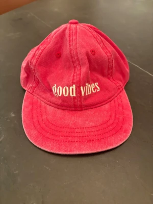 Rosa keps med brodyr 'good vibes' - Säljer en rosa keps i bomull med vit brodyrtexten 'good vibes' framtill. Klassisk böjd skärm och justerbar passform bak. Perfekt accessoar för en avslappnad och trendig stil❤️❤️ Kepsen är för liten för mig och då därför jag säljer 
