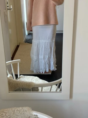 Vit långkjol med volangdetaljer - Säljer en vit långkjol med smock i midjan och volangdetaljer längst ner. Kjolen är i storlek 158/164🤍🤍