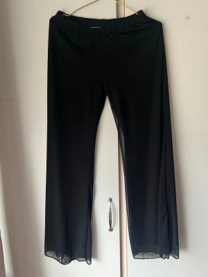 Svarta mesh leggings med vida ben - Säljer ett par svarta leggings med vida ben i meshmaterial. De har resår i midjan och är genomskinliga längs hela benen, vilket ger en trendig och luftig look. Perfekta att styla med oversized t-shirt eller crop top.