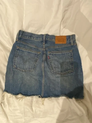 Levi's jeanskjol med fransig kant - Säljer denna söta jeans kjolen från Levis, som inte kommit till användning. Kontakta vid fler frågor eller bilder!