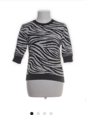 Stickad zebramönstrad tröja - Säljer en svartvit stickad tröja med zebramönster. Tröjan har rund halsringning, halvlånga ärmar och ribbade muddar vid ärmslut och nederkant. Perfekt för dig som vill sticka ut med ett djurinspirerat mönster.