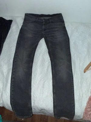 Grå jeans från Nudie Jeans Co - Säljer ett par grå jeans från Nudie Jeans Co i storlek 32/34. Jeansen har en klassisk rak passform och är tillverkade i slitstarkt denimtyg. Snygg tvättad look med subtila slitningar för en avslappnad stil.använda enstaka gånger. 