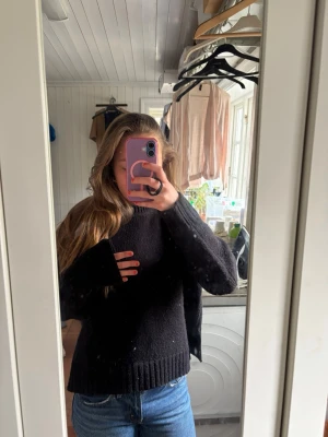 Svart stickad tröja från Zara - Mysig svart stickad tröja från Zara med klassisk rund halsringning och ribbade muddar vid ärmslut och nederkant. Perfekt till jeans eller kjol för en enkel och stilren look. Tillverkad i ett mjukt material som känns skönt mot huden.
