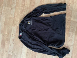 Svart långärmad topp från Clique - Svart långärmad topp från Clique med rund halsringning och diskret tryck på bröstet. Tillverkad i mjuk bomull som känns skön mot huden. Perfekt basplagg att styla med olika outfits.