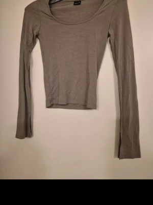 Beige långärmad topp i bomull - En basic beige långärmad topp med rundad halsringning och tight passform. Tillverkad i mjuk bomull som känns skön mot huden. Perfekt att styla lager på lager eller bära som den är för en clean look.