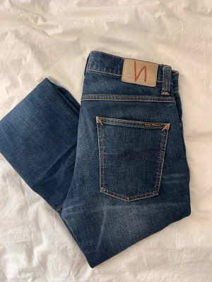 Nudie jeans - Säljer ett par mörkblå jeans från Nudie Jeans. Grim tim moddel! De har ett hål på framsidan som jag gjorde själv som gör de till en rikigt snygg slitning! 