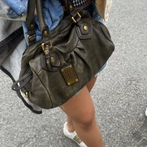 Grön Marc Jacobs väska - Säljer nu min så snygga mörkgröna Marc Jacobs väska. Modell baby groovee. Mycket bra skick med endast små tecken på användning! 