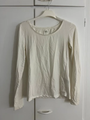 Vit långärmad topp från 157 - En enkel och stilren vit långärmad topp från 157. Toppen har rund halsringning och är tillverkad i mjuk bomull, perfekt att matcha med jeans eller kjol. Passar dig som gillar basic och clean stil.