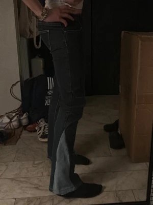 Mörkblå utsvängda jeans med kontrast - Säljer ett par mörkblå jeans med ljusare blå kontrastpaneler längs benen. Jeansen har utsvängda ben, klassiska fickor och synliga sömmar. Passar mig (170 cm), men lite korta i benen. Köpte på en loppis 💕Pris kan diskuteras under 130 kr💕