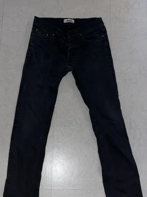 Svarta slimfit jeans från ACNE STUDIOS  - Säljer ett par svarta skinny jeans från Acne med klassisk femficksdesign och smal passform. Jeansen har bälteshällor, knappgylf och är tillverkade i ett mjukt denimtyg med 98% bomull, små slitningar 