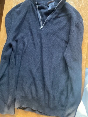 Svart stickad quarterzip H&M - Svart stickad tröja från H&M i slim fit-modell. Tröjan har halvzip i halsen och ribbade muddar vid ärmslut och nederkant. Perfekt för lager på lager och enkel att matcha med olika outfits.