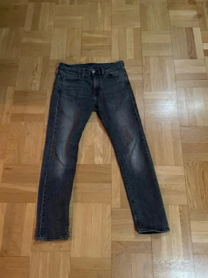 Mörkgrå Levi's raka jeans 501 - Snygga mörkgrå jeans från Levi's med klassisk femficksmodell och raka ben. Jeansen har en diskret tvättad look och är tillverkade i slitstark denim. Perfekta för dig som gillar en tidlös och avslappnad stil.