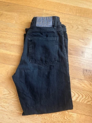 Svarta raka jeans från Bershka - Säljer ett par svarta jeans från Lee med rak passform och klassisk femficksdesign. Jeansen har en hög midja och Lee-lapp bak i midjan. Tillverkade i kraftig denim som ger en tidlös look. Perfekta för dig som gillar en avslappnad och stilren stil.