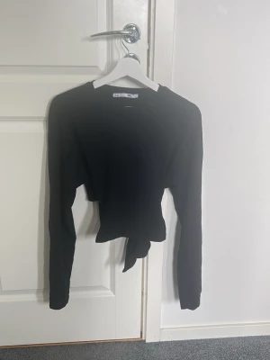Svart croppad topp med knyt - Hej. Jag säljer min svarta långaärmad tröja med knyt i ryggen. 
