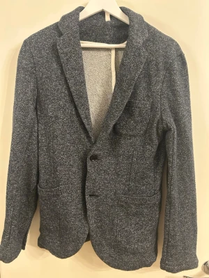 Overshirt  - Stilren mörkgrå kavaj/overshirt med två knappar framtill och klassiska slag. Kavajen har två framfickor och en bröstficka. Materialet är mjukt och något stretchigt, vilket ger en avslappnad men ändå dressad look. Bra skick, men tyvärr för liten för mig.