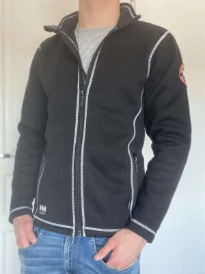 Svart fleecejacka från Helly Hansen - Svart fleecejacka från Helly Hansen. Storlek S och sitter som S. Lite nopprig på framsidan. Skriv vid funderingar📥