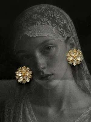 Stora blommiga örhängen i guld - Säljer ett par statement örhängen i form av stora blommor med guldfärgad metall och gnistrande stenar. Örhängena har en lyxig och iögonfallande design med flera facetterade detaljer som reflekterar ljuset snyggt. Perfekta för dig som vill sticka ut och addera lite glamour till din look.