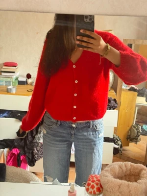Röd stickad kofta med knappar - Snygg röd kofta från Gina  med v-ringning och vita knappar framtill. Koftan är stickad och har en lite lösare passform med långa ärmar och ribbade muddar. 💕