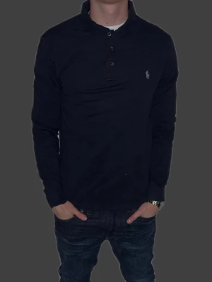 Mörkblå långärmad piké från Polo Ralph Lauren - Mörkblå långärmad piké från Ralph Lauren i storlek L.  Fint skick till ett bra pris. Nypris: 1995kr. Mitt pris: 349kr. Vid frågor eller funderingar, tveka inte att höra av dig.