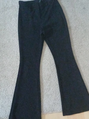 Svarta utsvängda byxor Vero Moda - Svarta utsvängda byxor från Vero Moda. Byxorna har hög midja och klassisk passform med vida ben. Perfekta för dig som gillar en trendig och stilren look. Materialet är mjukt och följsamt.