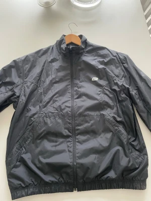  Nike vindjacka - Snygg svart vindjacka från Nike med dragkedja framtill och dragkedjor på fickorna. Jackan är knappt använd och är i storlek M och skick 9/10