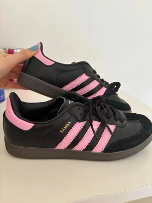Adidas Samba svart/rosa - Snygga Adidas Samba sneakers i svart med rosa ränder . Storlek 37 1/3, fint skick då de endast har använts en gång. Säljer då det tyvärr var fel storlek för mig💕