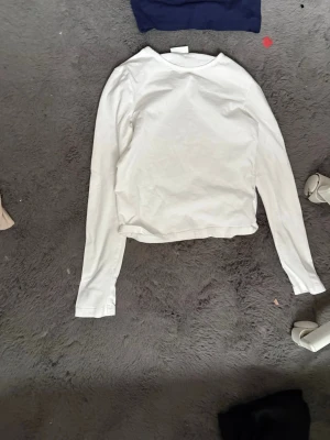 Vit långärmad topp från Kappahl - En enkel och stilren vit långärmad topp från Kappahl. Tillverkad i mjuk bomull med rund halsringning och rak passform. Perfekt att matcha med jeans eller kjol för en clean look. Har använt 1 gång❣️