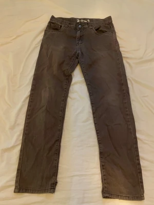 Grå raka jeans från Denim - Snygga grå jeans från Denim med rak passform och klassisk femficksdesign. Jeansen har bälteshällor och stängs med knapp och dragkedja. Perfekta för en avslappnad och trendig look. Dom är regulatoriska size också