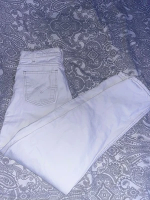 Vita Levi's 550 jeans straight fit - Säljer ett par vita Levi's 550 jeans med straight fit och klassisk femficksdesign. Jeansen har hög midja och tydliga sömmar på bakfickorna. Perfekta för en clean och stilren look. Materialet är kraftig denim i bomull.