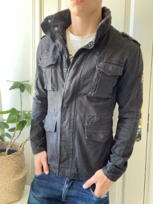 Superdry fieldjacket  - Superdry jacka - holy passform. Riktigt snygg. Inga defekter! Modellen i bilderna är 180 cm 75 kg och bär Storlek S , Kom med frågor! 🌟 (Kan gå ned i pris vid köp av paket 😉) 