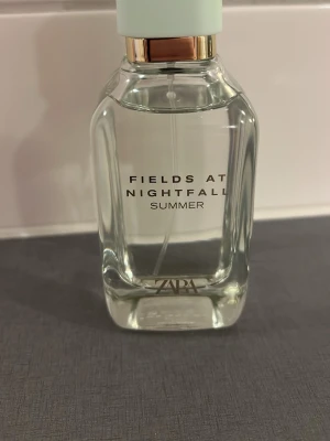 Zara Fields at Nightfall Summer parfym - Fräsch parfym från Zara med namnet Fields at Nightfall Summer. Flaskan är transparent med en ljus mintgrön kork och detaljer i guld. Modern och stilren design som passar perfekt på sminkbordet.