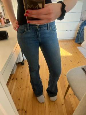 Blå bootcut jeans med klassisk look - Säljer ett par blå bootcut jeans med fina fickor och klassiska sömmar. Den har lite slitage längst ner på jeansen