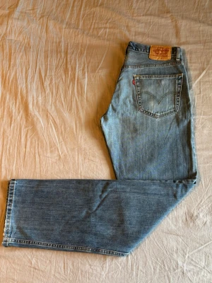 Levis 505 ljusblå - Klassiska ljusblå jeans från Levi's med rak passform. Storlek: W32 L34. Måtten: Midja - 40 cm Längd - 111 cm Innerbenslängd - 84 cm Fotöppning - 21 cm Lår - 30 cm