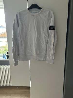 Calvin Klein sweatshirt - En vit Calvin Klein sweatshirt med tjockt material. Den har en CK patch på ärmen.