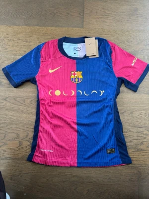 Barça matchtröja Lewandowski Nike - Brand new Nike FC Barcelona 2023-24 El Clásico Special Edition jersey, featuring a unique split blue and pink design with golden crescent moon graphics on the front. This authentic Dri-FIT ADV kit proudly displays Lewandowski's #9 on the back, along with the UNHCR ACNUR sponsor.  ⭐️ Condition : 10/10 🎨 Color : Blue/Pink/Gold 📦 Fast and careful shipping 