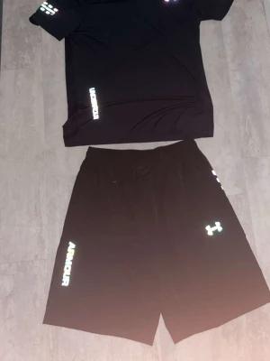 Svart träningsset från Under Armour - Säljer ett svart träningsset från Under Armour med t-shirt och shorts. 